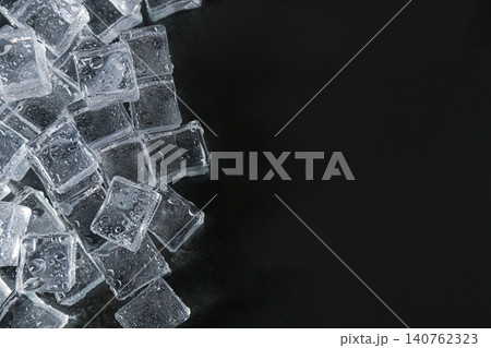 Crystal clear ice cubes with water drops on black background, flat lay. Space for text Crystal clear ice cubes with water drops on black background, flat lay. Space for text 140762323