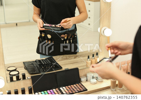 Professional makeup artist with eyeshadow palette and belt organizer full of tools in studio, closeup Professional makeup artist with eyeshadow palette and belt organizer full of tools in studio, closeup 140762355