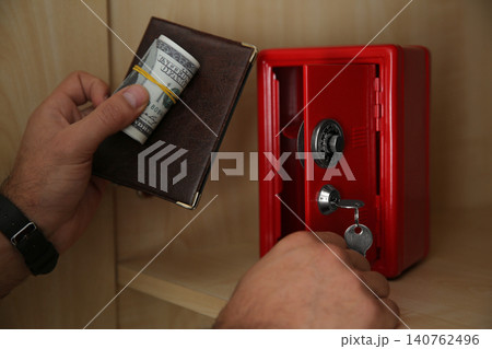 Man putting passport and money into small steel safe, closeup Man putting passport and money into small steel safe, closeup 140762496