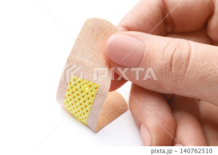 Woman putting sticking plaster on white background, closeup. First aid item 140762510