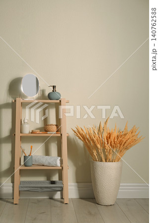Wooden shelving unit with toiletries near light wall indoors. Bathroom interior element 140762588