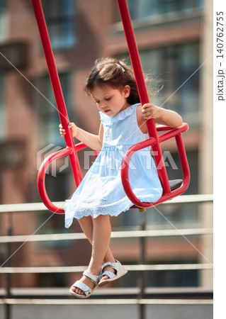 Child enjoying playtime on a playground swing. Innocence and joy during childhood summer outdoor activities Child enjoying playtime on a playground swing. Innocence and joy during childhood summer outdoor activities 140762755