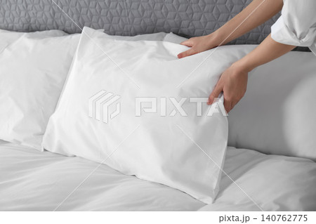 Woman fluffing soft pillow in bedroom, closeup 140762775