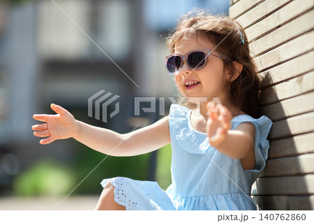 Young girl smiling with arms open, enjoying a happy and carefree childhood moment outdoors on a sunny summer day 140762860