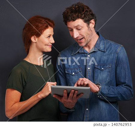 Tablet, man and woman in studio together with casual style, connection and networking for creative professional. Internet, communication and team with digital app for online search on dark background Tablet, man and woman in studio together with casual style, connection and networking for creative professional. Internet, communication and team with digital app for online search on dark background 140762953