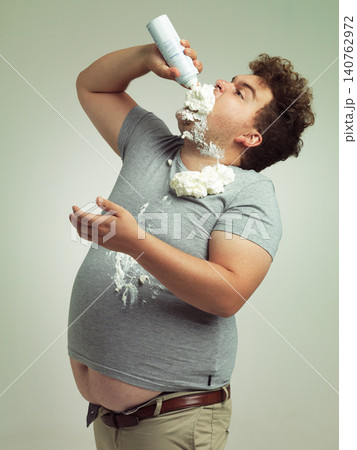 Sweet, dessert and man with whipped cream for eating in studio background, addiction and unhealthy for plus size male person. Guy, health problem and risk for diabetes with sugar and cholesterol Sweet, dessert and man with whipped cream for eating in studio background, addiction and unhealthy for plus size male person. Guy, health problem and risk for diabetes with sugar and cholesterol 140762972