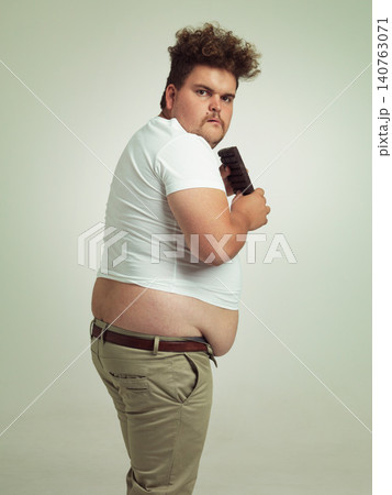 Chocolate, portrait and plus size man with junk food, dessert and candy in a studio. Funny, sweet and unhealthy snack for eating with greed gesture and hungry male person with green background Chocolate, portrait and plus size man with junk food, dessert and candy in a studio. Funny, sweet and unhealthy snack for eating with greed gesture and hungry male person with green background 140763071