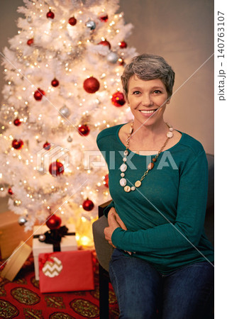 Christmas, tree and portrait of mature woman in home for holiday with presents on vacation. Happy, person and relax on with festive xmas decoration and gift box in living room and enjoy retirement Christmas, tree and portrait of mature woman in home for holiday with presents on vacation. Happy, person and relax on with festive xmas decoration and gift box in living room and enjoy retirement 140763107