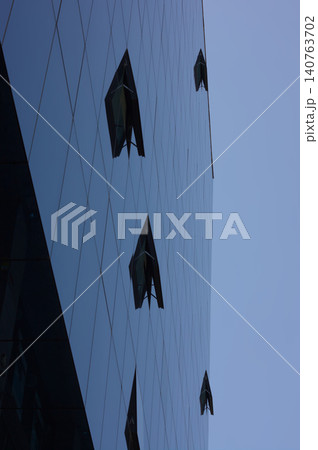 Glass building windows reflecting sky blue 140763702