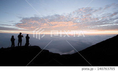Silhouette of a group climbers looking at the sunrise in the mountain Silhouette of a group climbers looking at the sunrise in the mountain 140763705