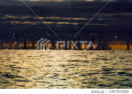 A lot of sailing boats through splashing water at sunset, Sailing regatta in the Gulf of Finland at sunset, hot race of several yachts, teamwork A lot of sailing boats through splashing water at sunset, Sailing regatta in the Gulf of Finland at sunset, hot race of several yachts, teamwork 140763889