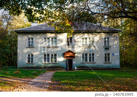 Old wooden house with faded paint, nestled among autumnal trees. A rustic charm, tranquil scene, and vintage architecture in warm sunlight Old wooden house with faded paint, nestled among autumnal trees. A rustic charm, tranquil scene, and vintage architecture in warm sunlight 140763995