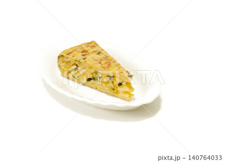 Authentic Spanish potato and egg omelet slice with zucchini on a white plate. Ideal food photography for traditional restaurant menus, culinary websites, food delivery, and catering ads. 140764033