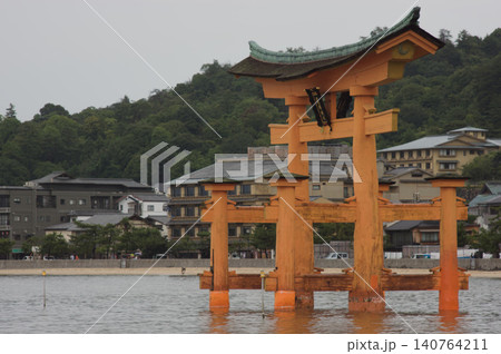 Itsukushima shrine torii gate with Miyajima village in the background. 140764211
