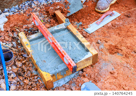 Workers level concrete slab with tools materials at construction site. 140764245