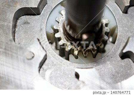 Close-up view of an electric bicycle motor planetary gear assembly featuring a metallic sun gear engaged with white nylon satellite gears on a maintenance bench Close-up view of an electric bicycle motor planetary gear assembly featuring a metallic sun gear engaged with white nylon satellite gears on a maintenance bench 140764771