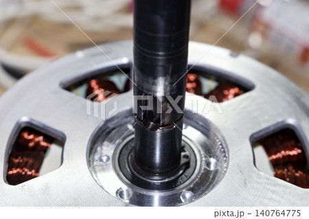 Close-up of a steel keyed shaft on an electric bicycle geared motor hub, featuring visible copper coil windings and precision engineering components for e-bike drivetrain assembly Close-up of a steel keyed shaft on an electric bicycle geared motor hub, featuring visible copper coil windings and precision engineering components for e-bike drivetrain assembly 140764775