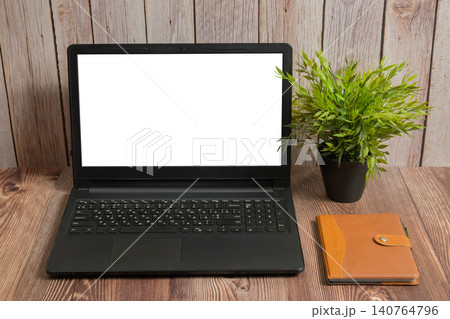 laptop with white screen notebook and plant on wooden table laptop with white screen notebook and plant on wooden table 140764796