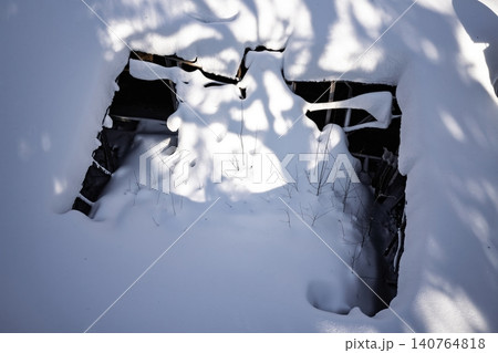 Aerial view of a collapsed roof, heavily blanketed by pristine winter snow, showing deep structural damage. Cold decay Aerial view of a collapsed roof, heavily blanketed by pristine winter snow, showing deep structural damage. Cold decay 140764818