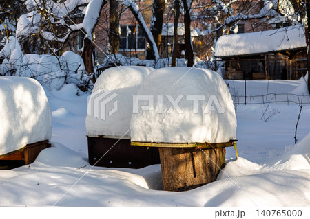 Wooden garden tables heavily covered with thick fresh snow after a winter blizzard, standing in a quiet residential backyard during a sunny cold day with crisp shadows on the ground Wooden garden tables heavily covered with thick fresh snow after a winter blizzard, standing in a quiet residential backyard during a sunny cold day with crisp shadows on the ground 140765000
