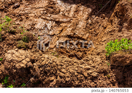 Raw excavated soil texture in a field featuring heavy tread marks and messy dirt chunks from construction work leaving a rugged earthy pattern on the disturbed ground surface Raw excavated soil texture in a field featuring heavy tread marks and messy dirt chunks from construction work leaving a rugged earthy pattern on the disturbed ground surface 140765053