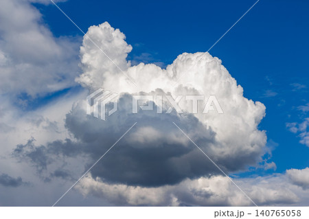 Single fluffy white cumulus cloud floating in a vibrant deep blue summer sky, showcasing dramatic shadows and bright highlights with soft textures against the vast clear atmosphere Single fluffy white cumulus cloud floating in a vibrant deep blue summer sky, showcasing dramatic shadows and bright highlights with soft textures against the vast clear atmosphere 140765058