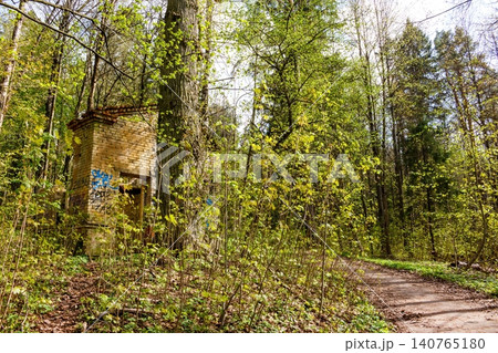Brick ruins, crumbling yet vibrant with graffiti, nestle amidst lush spring foliage. An eerie, forgotten structure in a serene forest park, blending history and nature: Russia - April 25, 2024 140765180