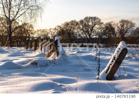 A stark winter scene with decaying fence posts buried in deep snow drifts, evoking themes of former Soviet labor camps and northern isolation A stark winter scene with decaying fence posts buried in deep snow drifts, evoking themes of former Soviet labor camps and northern isolation 140765190