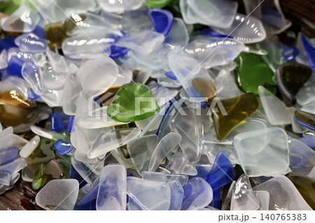 A shimmering heap of vibrant, artificially tumbled glass pieces. Frosted, smooth sea glass replication in blues, greens, and whites, perfect for craft or decor A shimmering heap of vibrant, artificially tumbled glass pieces. Frosted, smooth sea glass replication in blues, greens, and whites, perfect for craft or decor 140765383