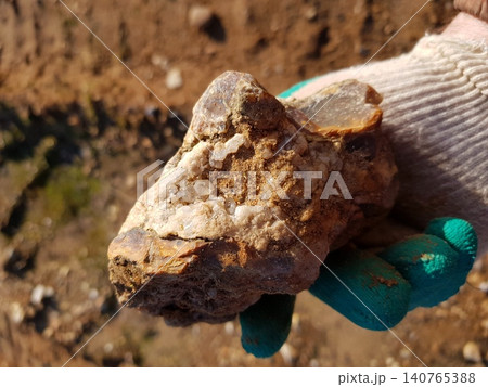 Gloved hand presents a fascinating rough flint concretion, boasting sparkling quartz crystals unearthed during a geological hike Gloved hand presents a fascinating rough flint concretion, boasting sparkling quartz crystals unearthed during a geological hike 140765388