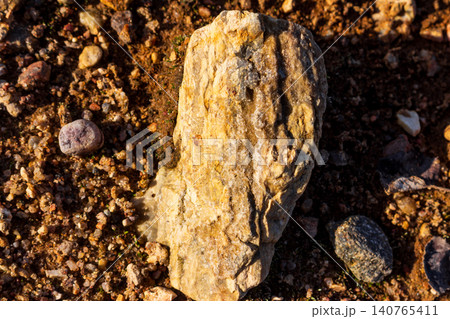 Vibrant flint rock bathed in spring sun, sparkling with tiny quartz crystals. Earthy ground texture, raw mineral beauty 140765411
