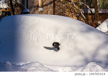 Vehicle entombed by heavy winter snow, just a side mirror visible. Harsh cold season, frosty morning, unexpected snowfall Vehicle entombed by heavy winter snow, just a side mirror visible. Harsh cold season, frosty morning, unexpected snowfall 140765414