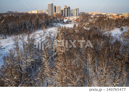 Stunning aerial view of a frosty winter forest, snow-covered trees reaching towards a distant cityscape under golden hour light, contrasting nature and urban development Stunning aerial view of a frosty winter forest, snow-covered trees reaching towards a distant cityscape under golden hour light, contrasting nature and urban development 140765477