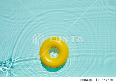 Yellow inflatable ring floating on blue swimming pool water Yellow inflatable ring floating on blue swimming pool water 140765716