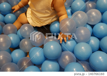 青いボールプールで遊ぶ1歳の幼児の体の一部。屋内遊び場。 青いボールプールで遊ぶ1歳の幼児の体の一部。屋内遊び場。 140766160