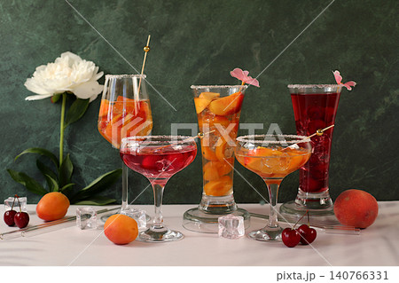Apricot punch, cherry martini, mixed sangria, and juices on ice for a party. A modern still life with a variety of summer alcoholic cocktails and peonies against sunny background. minimalist concept Apricot punch, cherry martini, mixed sangria, and juices on ice for a party. A modern still life with a variety of summer alcoholic cocktails and peonies against sunny background. minimalist concept 140766331