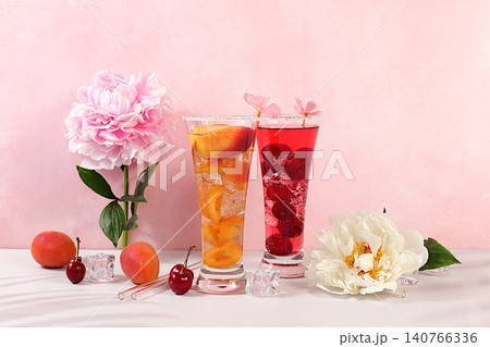 Modern still life with a variety of summer alcoholic cocktails and peonies against a sunny background. Apricot and cherry punch, mixed sangria, and iced juices for a party. Minimalist concept Modern still life with a variety of summer alcoholic cocktails and peonies against a sunny background. Apricot and cherry punch, mixed sangria, and iced juices for a party. Minimalist concept 140766336