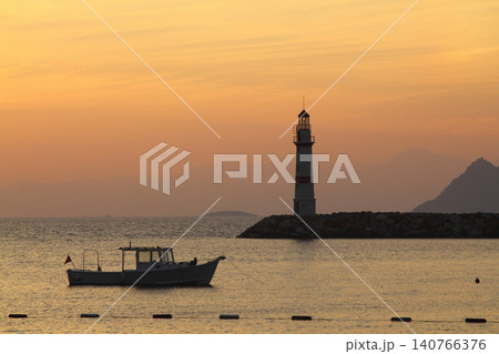 Seascape at sunshine. Lighthouse and sailings on the coast. Seaside town of Turgutreis Seascape at sunshine. Lighthouse and sailings on the coast. Seaside town of Turgutreis 140766376