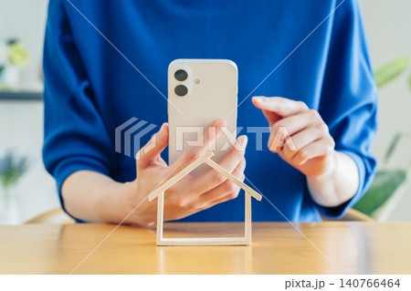 住宅模型とスマホを持つ若い女性の手元 住宅模型とスマホを持つ若い女性の手元 140766464