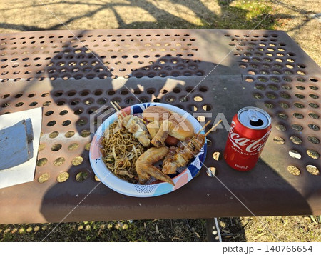 屋外のベンチで楽しむ焼きそばや焼き鳥と缶コーラのランチ風景 140766654