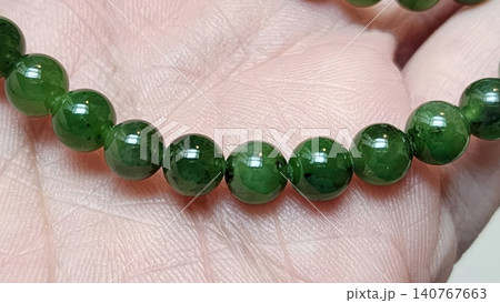 Natural Dark Green Jade Gemstone Round Bead Bracelet on Human Palm Natural Dark Green Jade Gemstone Round Bead Bracelet on Human Palm 140767663