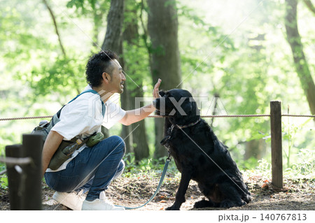 犬と見つめ合う仲良しの散歩を楽しむ男性 公園で大型犬のペットに躾をするライフスタイル ハイタッチ 犬と見つめ合う仲良しの散歩を楽しむ男性 公園で大型犬のペットに躾をするライフスタイル ハイタッチ 140767813