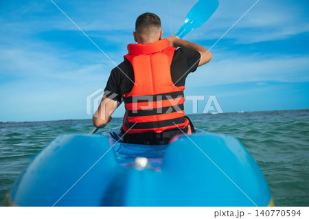 Man paddles a kayak in clear blue waters on a sunny day 140770594