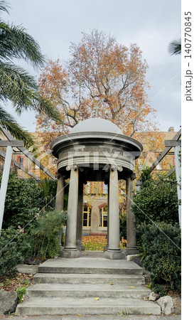 A symmetrical low-angle perspective of a historic stone rotunda shrine with a dome and cross. 140770845