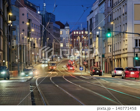Bustling urban evening scene showcasing moving vehicles illuminated by flowing city lights and motion Bustling urban evening scene showcasing moving vehicles illuminated by flowing city lights and motion 140771458