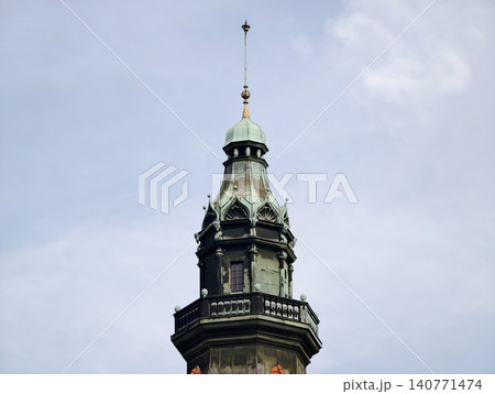 Ancient municipal tower adorned with gilded accents and layered spires visible against overcast sky Ancient municipal tower adorned with gilded accents and layered spires visible against overcast sky 140771474