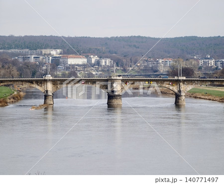 Tranquil river crossing with stone supports. Scenic view of old bridge with nature and structures Tranquil river crossing with stone supports. Scenic view of old bridge with nature and structures 140771497