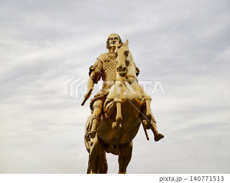 Cinematic depiction of powerful historical rider on textured bronze horse surrounded by tempestuous weather 140771513