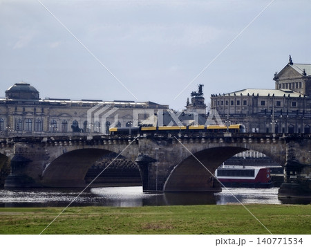 River scene showcasing busy urban transportation. Vibrant cityscape with tram crossing over river bridge 140771534