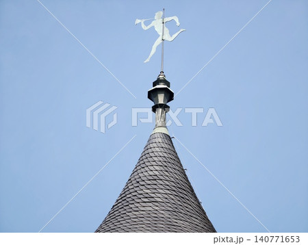 Vivid conical tower with shiny copper vane. Cheerful travel image showing sunlit turret and blue sky Vivid conical tower with shiny copper vane. Cheerful travel image showing sunlit turret and blue sky 140771653